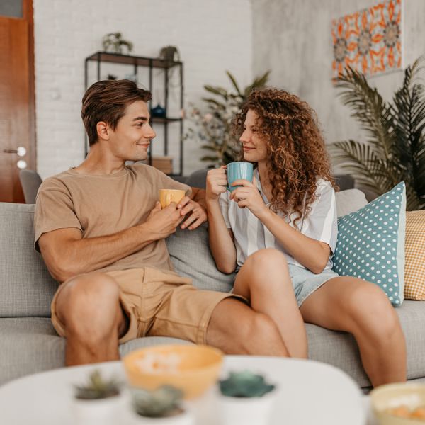 happy young couple sitting on the sofa in the living room and drinking coffee