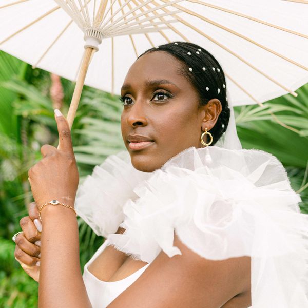 Bride with glowing makeup, neutral nails, and pearls in hair