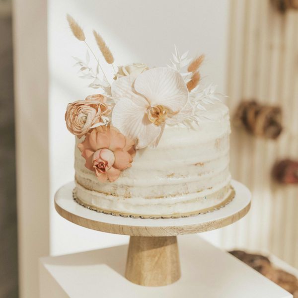 Single tier white cake with orchid, pink roses, and dried white foliage