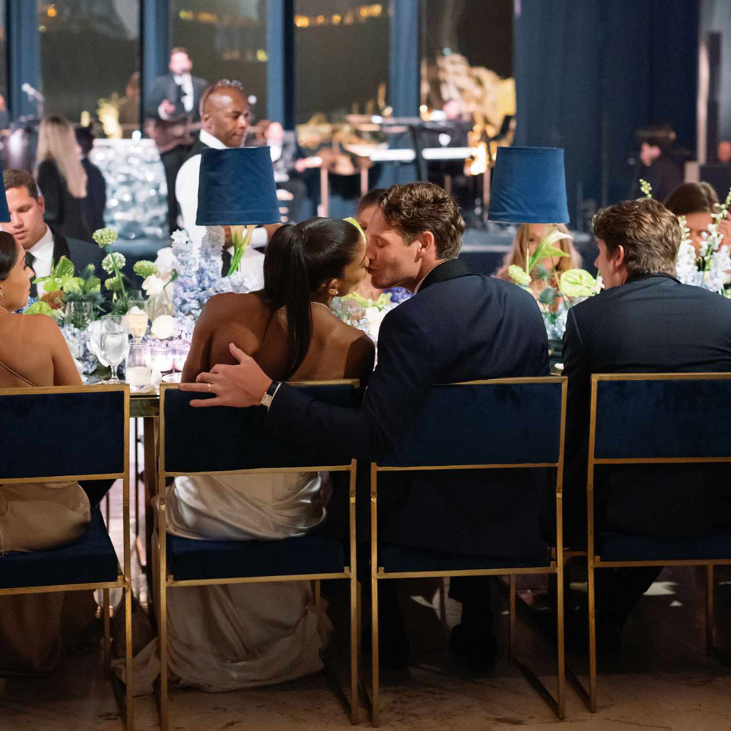 Couple Shares a Kiss While Seated at Their Dinner Table During Their Wedding Reception