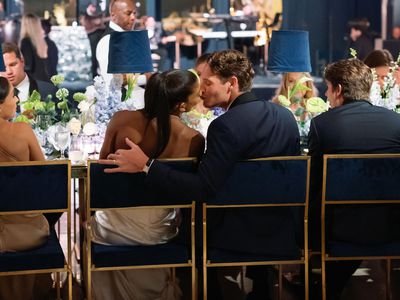 Couple Shares a Kiss While Seated at Their Dinner Table During Their Wedding Reception