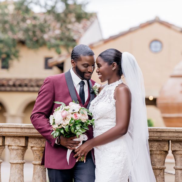 Groom in a burgundy tux and bride in a high-neck floral dress