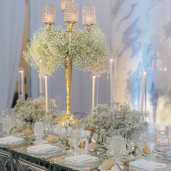Wedding Reception Tablescape With Baby's Breath Centerpieces, White Taper Candles, and Gold Candelabra