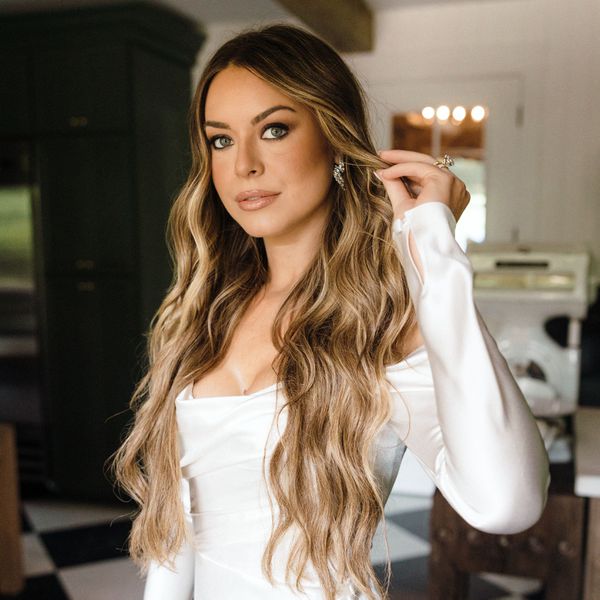 bride wearing long hair in waves and long-sleeved, off-the-shoulder wedding dress with buttons