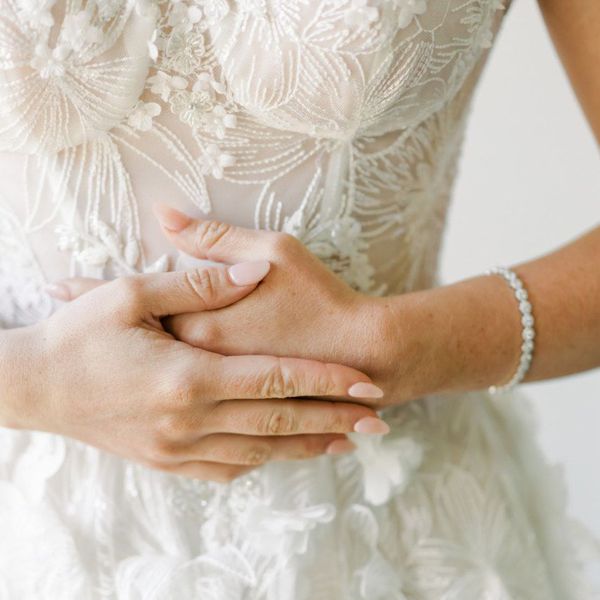 Closeup of brideâs hands with light pink nail polish
