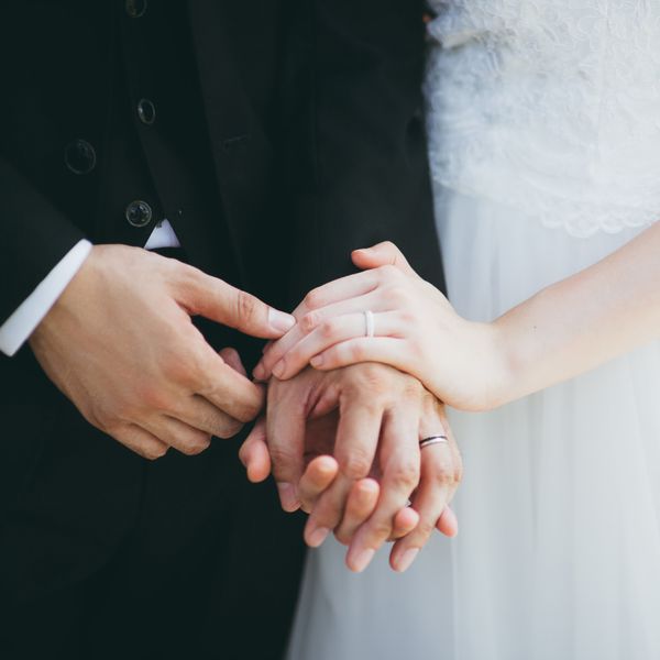 Closeup of Bride and Groom Holding Hands With Wedding Bands On