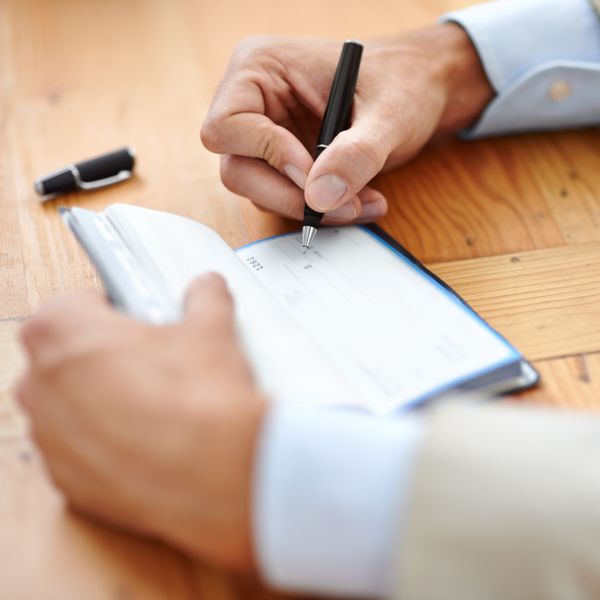 Closeup of Man in Suit Sitting at Table and Making Out a Check