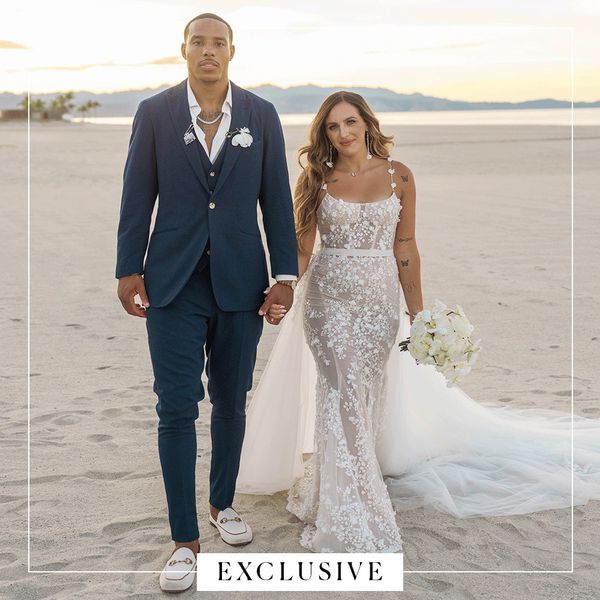 Desmond Bane in Navy Suit Posing With Tatum Bane in Lace Wedding Dress on Beach