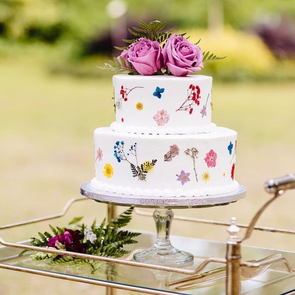Publix wedding cake with two-tiers of white cake, pressed florals, and fresh pink roses on top