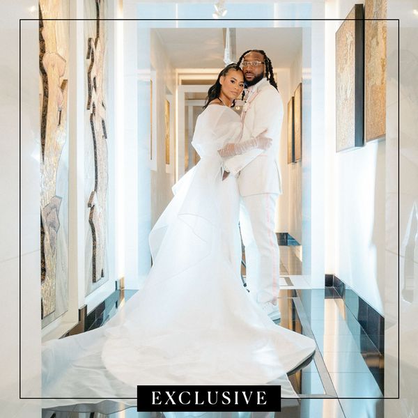 Bride in White Wedding Dress Posing With Groom in White Tuxedo in Hallway