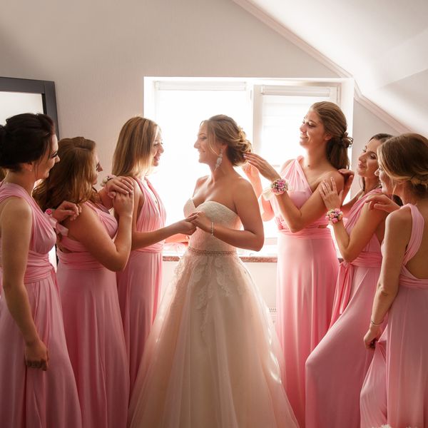 Bridesmaids in Pink Dresses Helping Bride in Strapless Wedding Dress Get Ready
