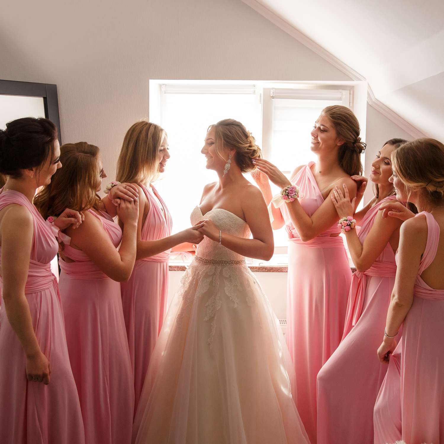 Bridesmaids in Pink Dresses Helping Bride in Strapless Wedding Dress Get Ready