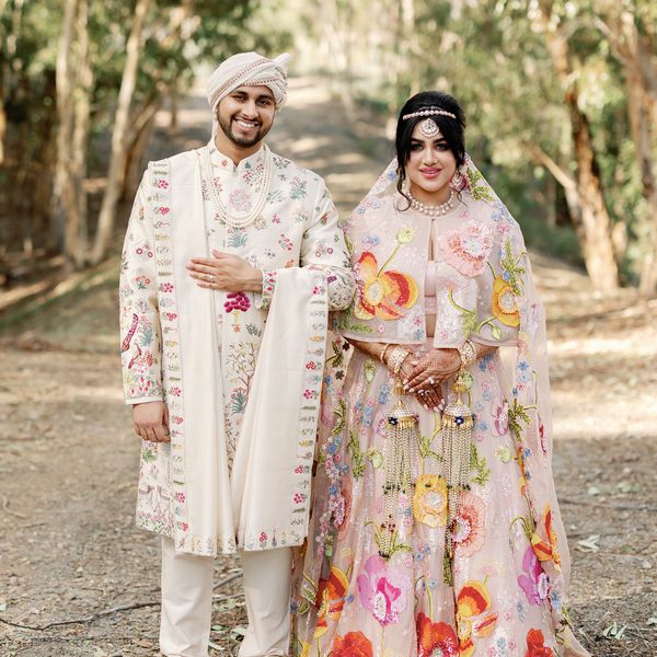 Bride in Pink Indian Dress With Colorful Embroidery Posing With Groom in Beige Kurta with Colorful Embroidery
