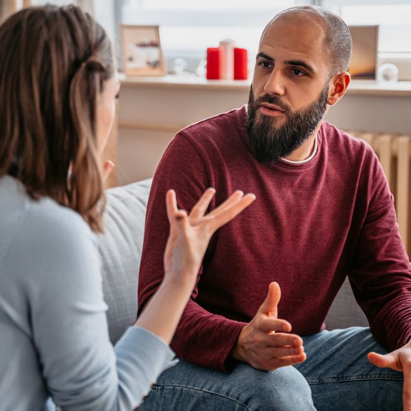 Couple With Hands Raised Arguing on Couch at Home