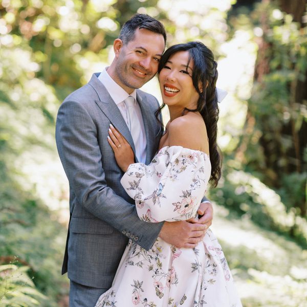 Bride in Strapless White Floral Wedding Dress Posing With Groom in Grey Suit