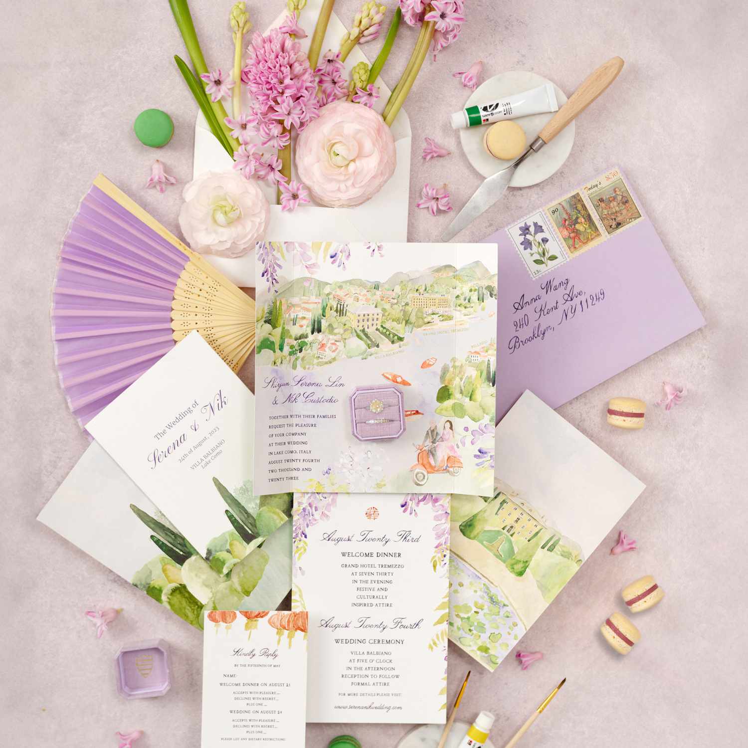 Lavender Garden Themed Wedding Invitations Next To Rings, Macaroons, Lavender Hand Fan, and Pink Flowers