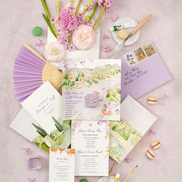 Lavender Garden Themed Wedding Invitations Next To Rings, Macaroons, Lavender Hand Fan, and Pink Flowers