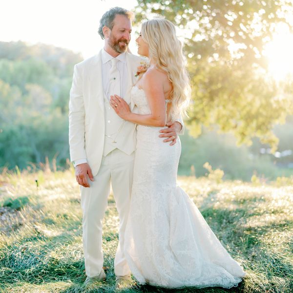 Bride in Wedding Dress and Hair Down Posing With Groom in White Suit