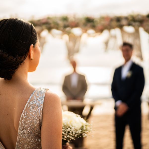Back of Bride Walking Down the Aisle at Beach Wedding Ceremony With Groom Standing at the Altar