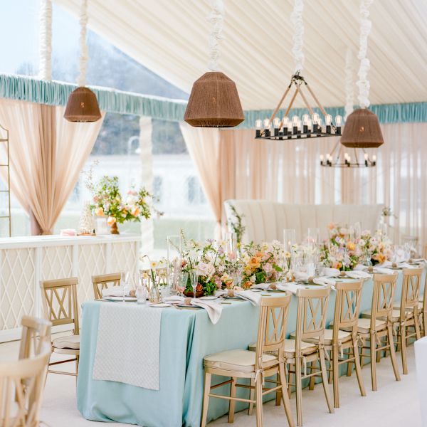 Reception tent with nautical light fixtures and tables covered in blue linens