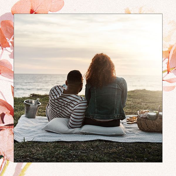A couple sitting in front of the ocean with champagne.