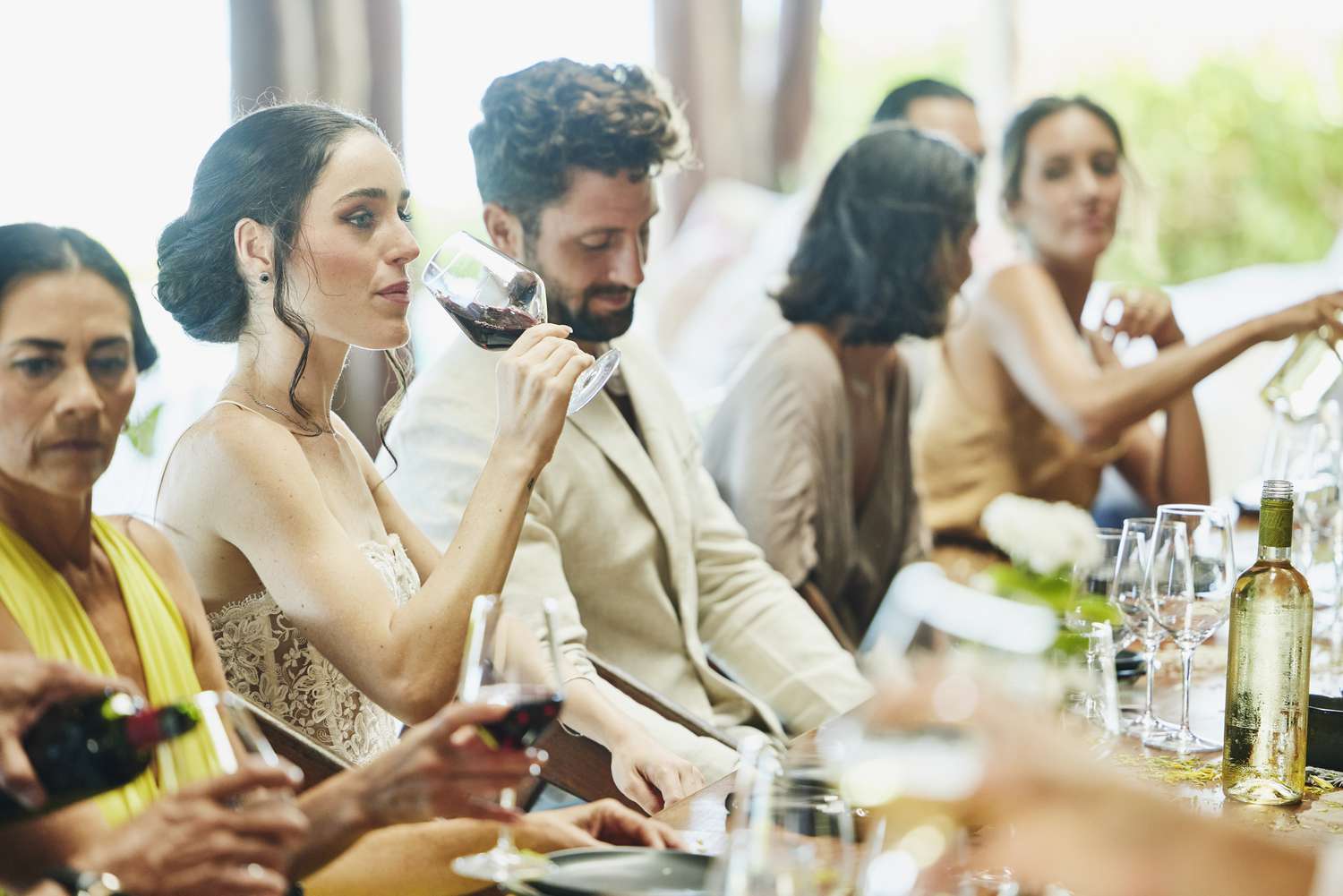 Bride Sipping Wine and Groom Looking Down While Sitting at Dinner Table