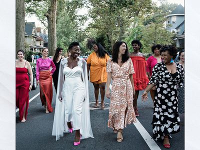 Bride and bridesmaids laughing while walking down the street