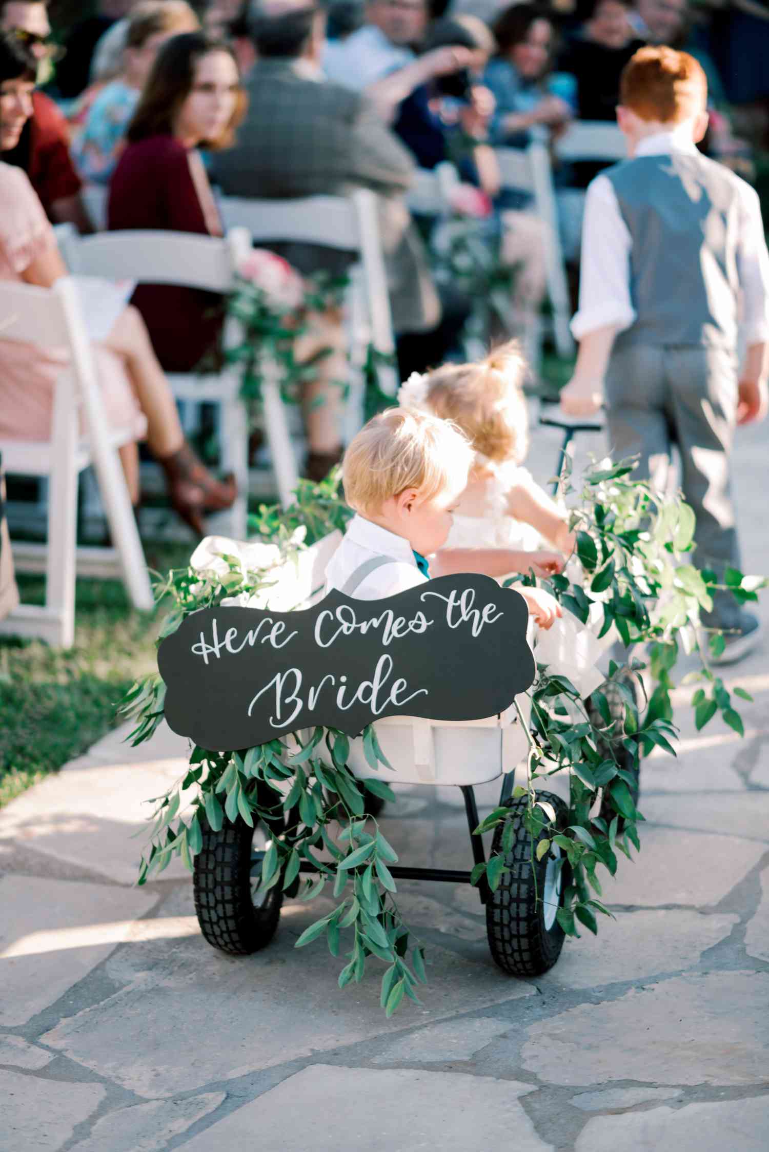 Ring Bearer and Flower Girl in Wagon With Greenery and Green Sign