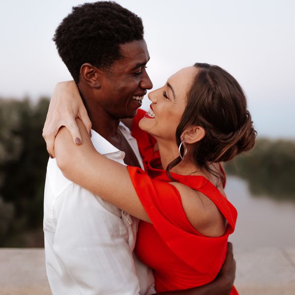 Smiling Couple Looking Into Each Other's Eyes and Wrapping Their Arms Around One Another