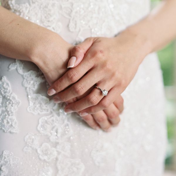 Bride With French Manicure Wearing Round-Cut Diamond Engagement Ring on Thin White Gold Band