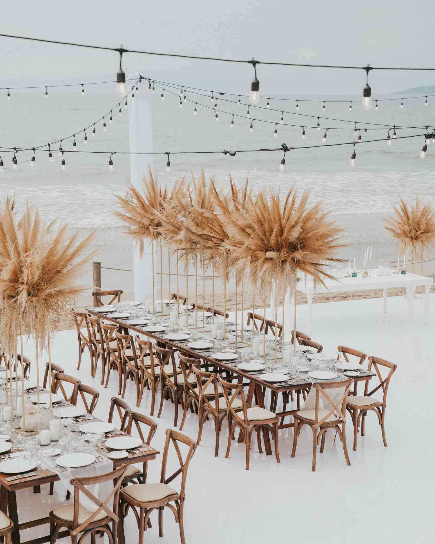 oceanfront reception with tall pampas grass centerpieces and wooden chiavari chairs