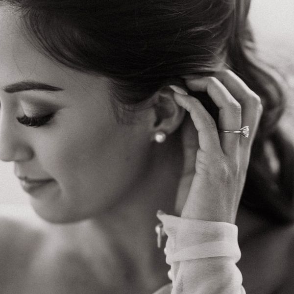 black and white photo of bride with diamond ring and pearl earrings