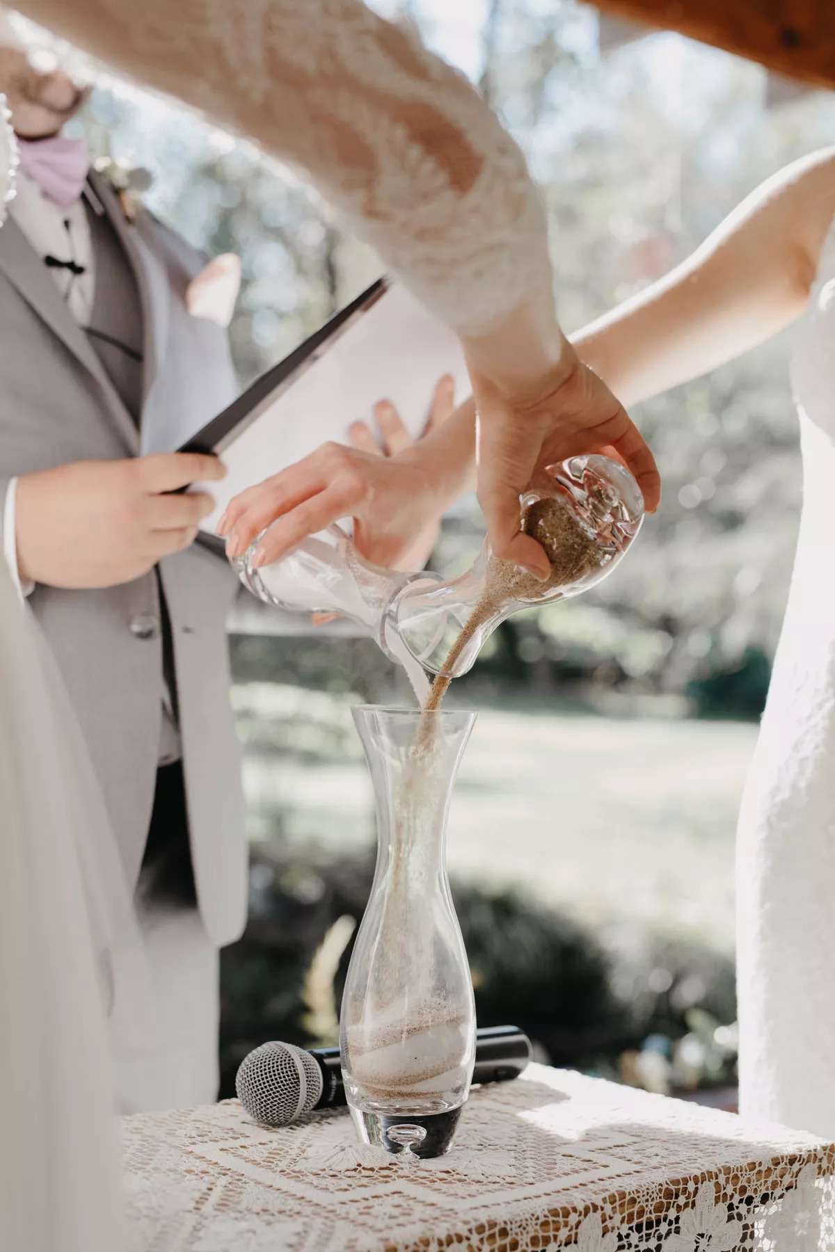 Bride and groom pouring sand into vessel during ceremony
