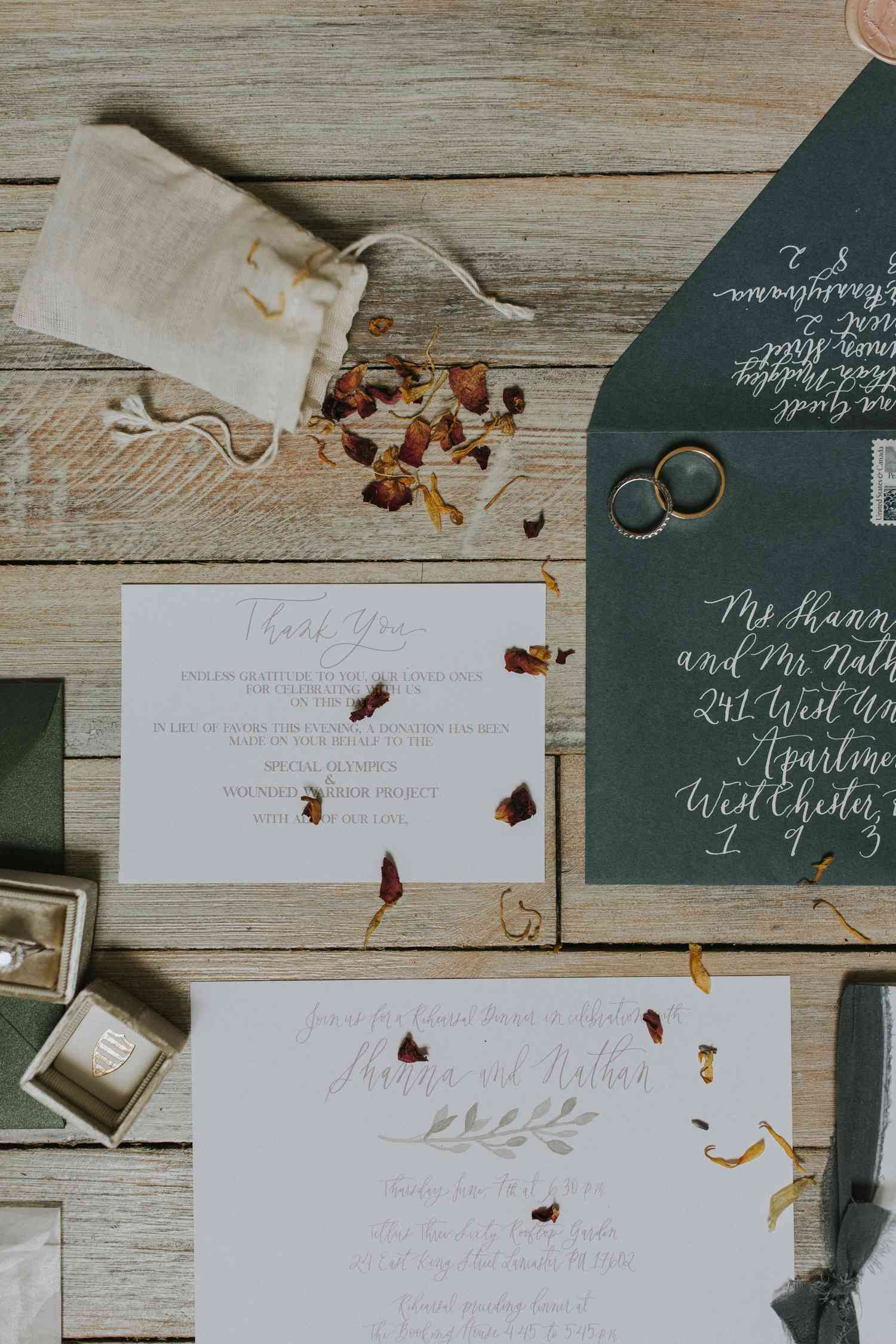 A floral wedding invitation suite for a fall wedding with dried flower petals and wedding rings.
