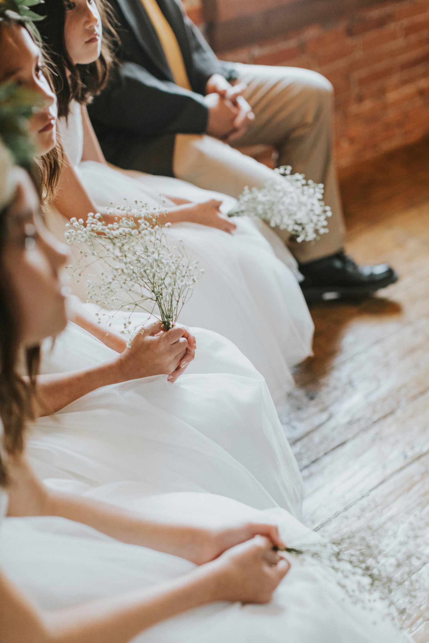 Flower girls and junior bridesmaids in white dresses holding posies of babys breath