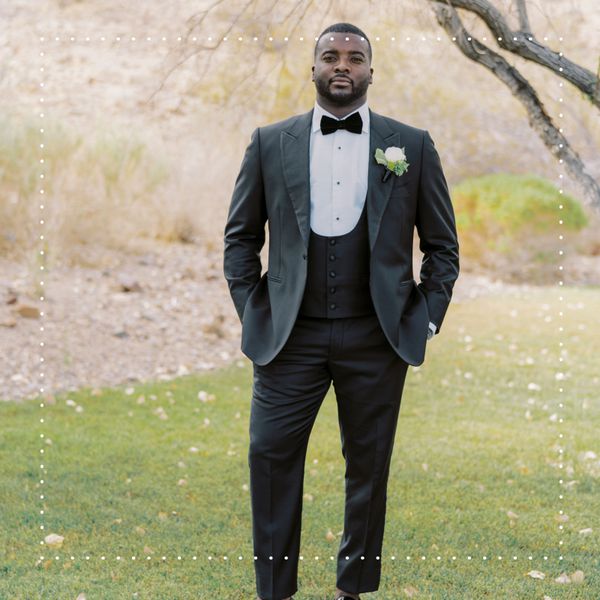 groom wearing a black tuxedo with a bow tie and boutonniere