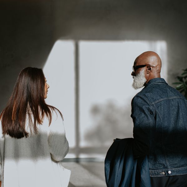 Conceptual image of a woman and man, separated by the shadows on the wall, yet standing next to one another