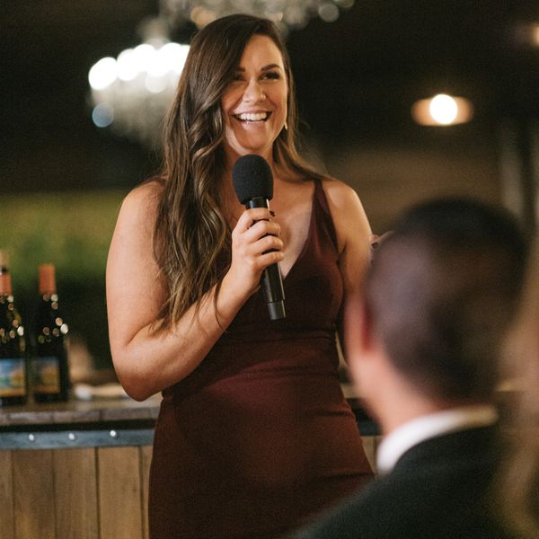 a young woman dressed in burgundy giving a wedding speech