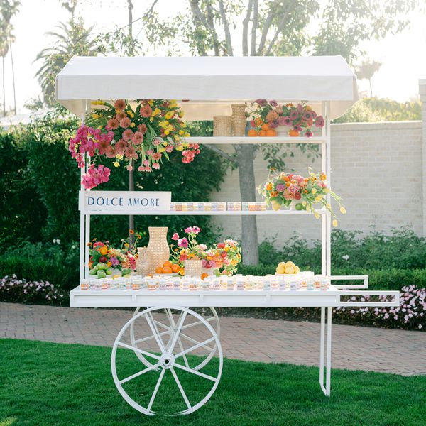 White Cart with Fresh Flowers and Pastel-Colored Candy Box Favors at Wedding Reception