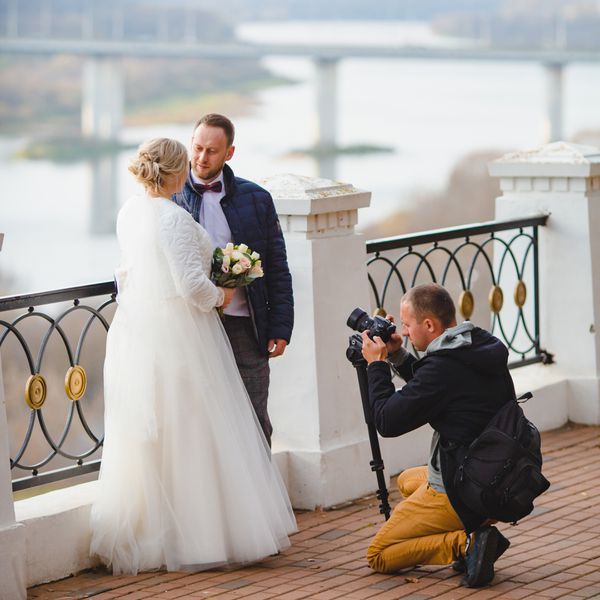 Wedding videographer taking video of bride and groom overlooking water