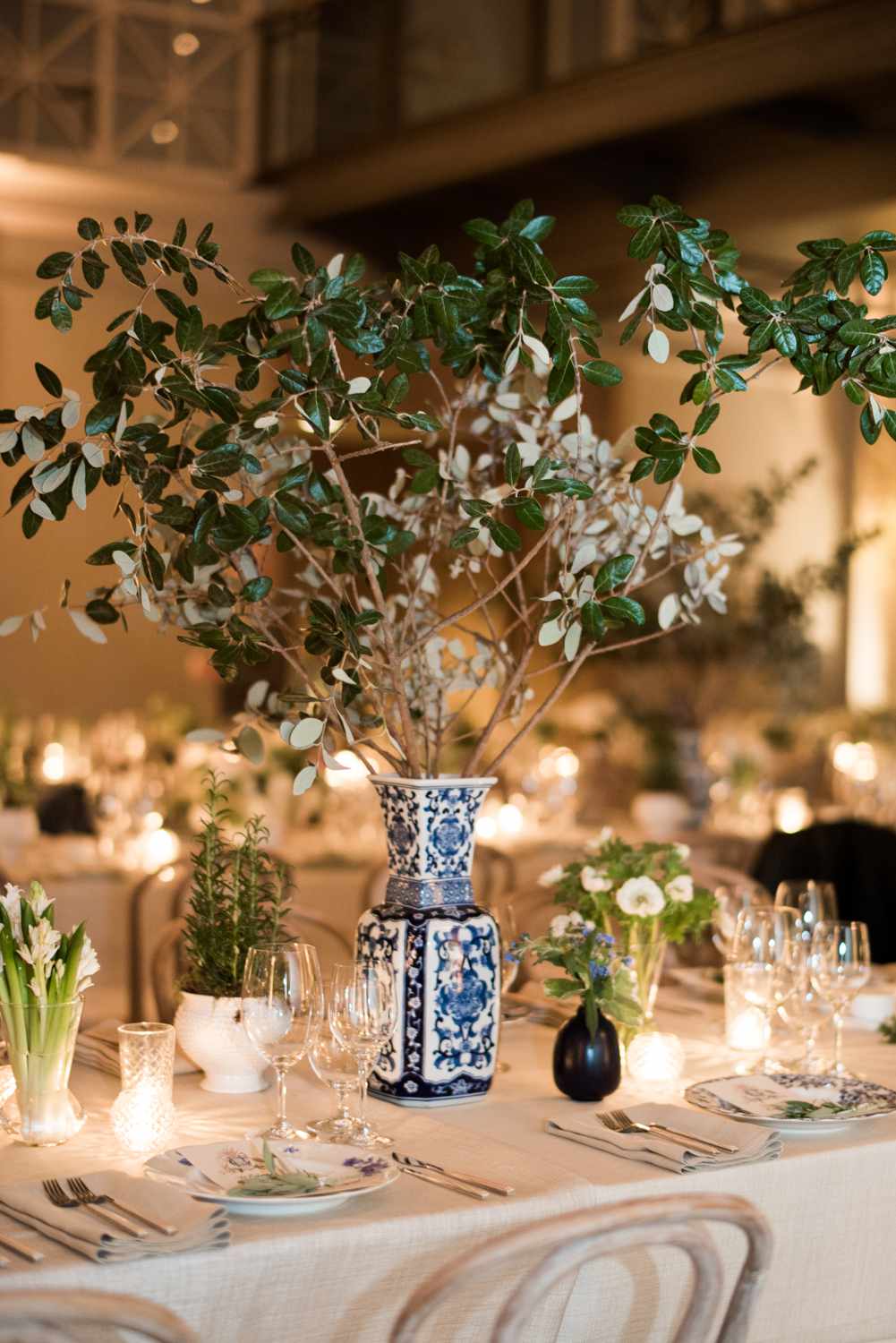 Chinoiserie Vase With Branches in the Middle of Beige Linens, Accompanied by Smaller Floral Arrangements