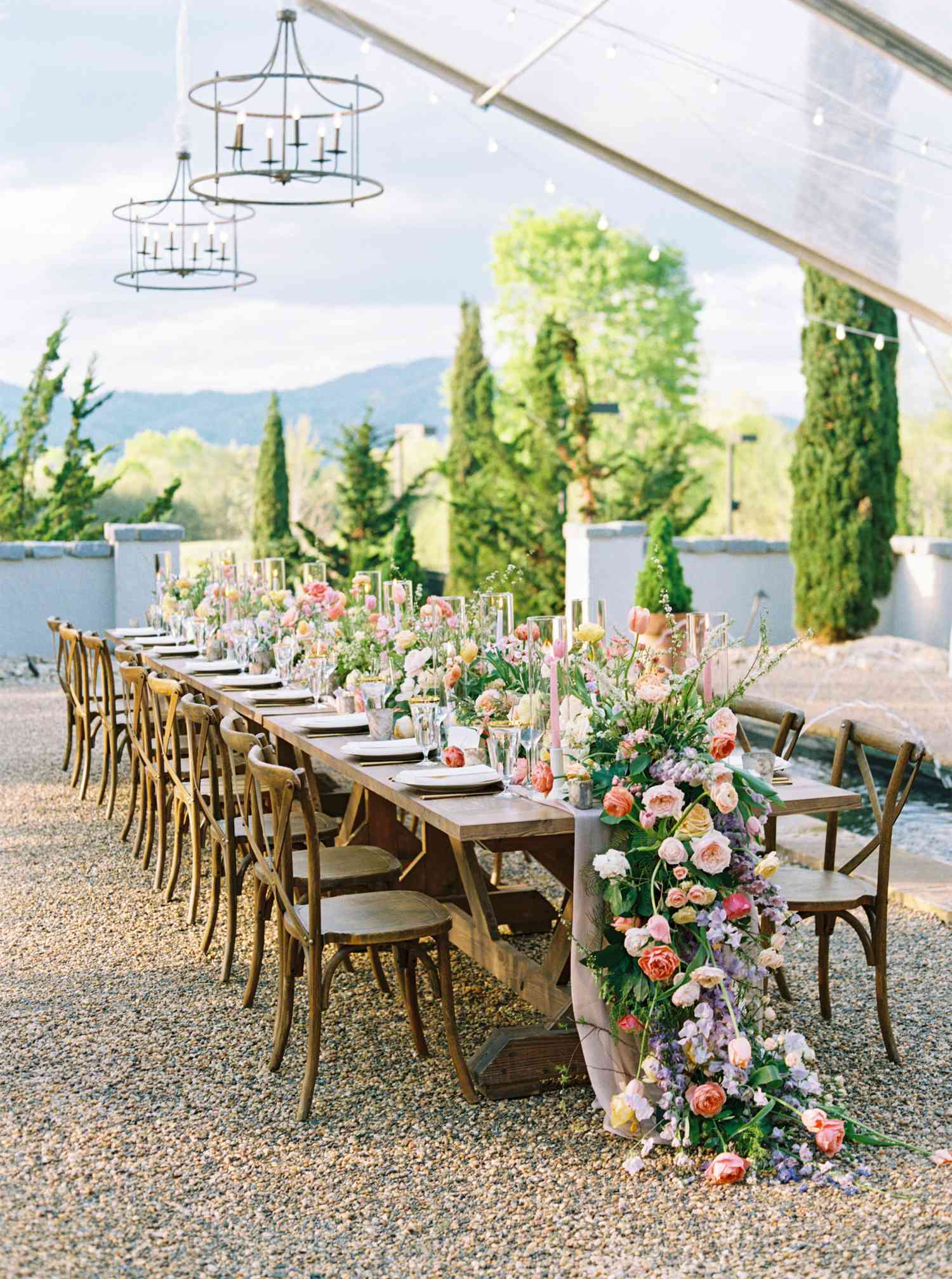 Long Reception Table with Overflowing Floral Garland Centerpiece Comprised of Greenery,, Roses, Tulips, and More