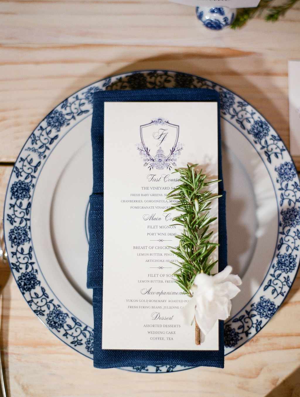 Monogrammed menus paired with herbs and flower on chinoiserie plate with navy linens