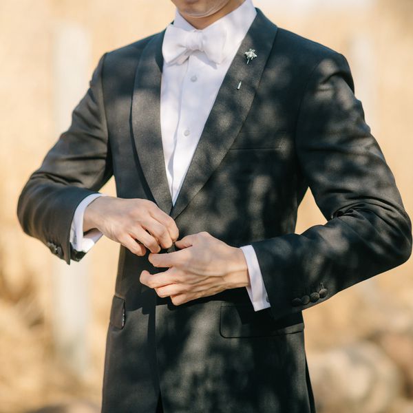 groom buttoning his jacket