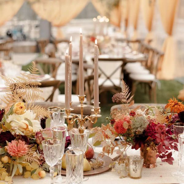 A fall-inspired tablescape with candelabras, golden ferns, and jewel-tone flowers