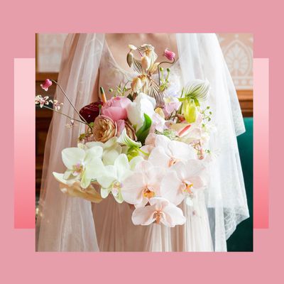 Bride with cascading, tiered veil holding soft and colorful bouquet of pastel orchids and assorted blooms