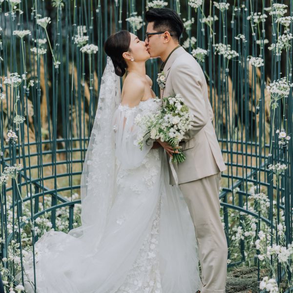 bride and groom kissing under an alter of daisies