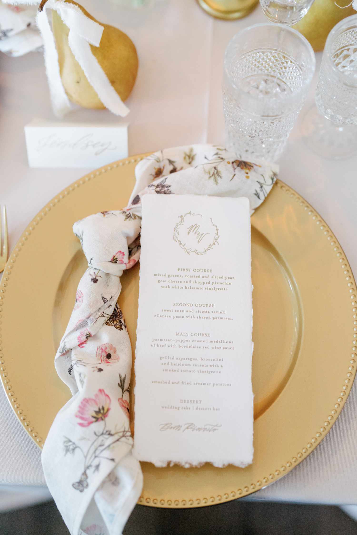 Wedding tablescape with gold charger, menu card, pear place card, and printed floral napkin