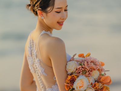 Bride Holding Bouquet of Orange, Peach, and Cream Flowers on the Beach