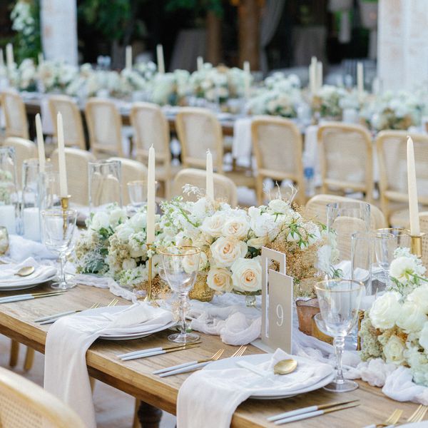 Wooden Wedding Reception Tables With Low Centerpieces of Roses, Ranunculus, Astilbe, and Greenery